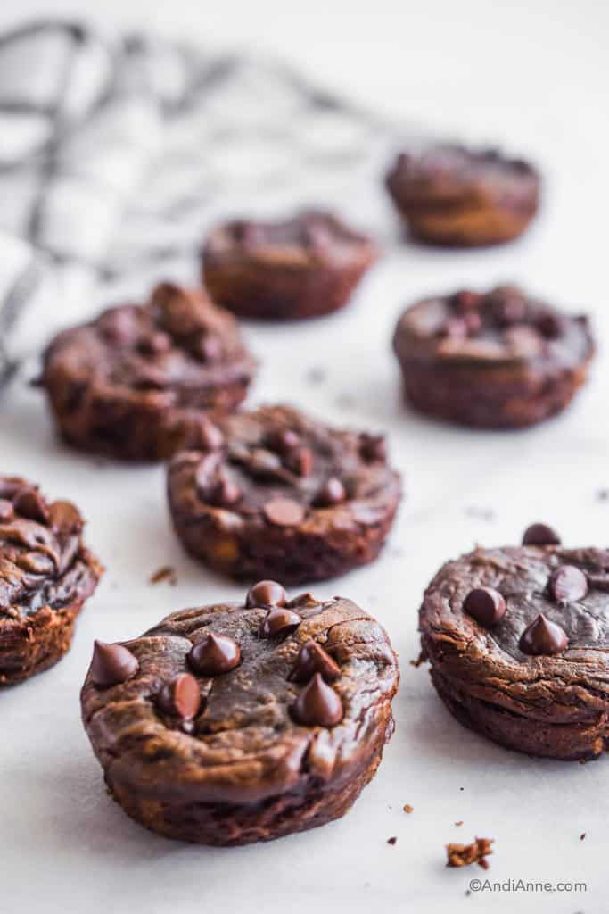 side detail of flourless banana chocolate muffins on white table with plaid kitchen towel in the background