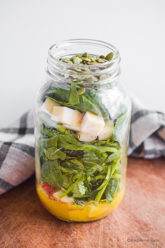apple and cheese salad in mason jar with kitchen towel and on a cutting board