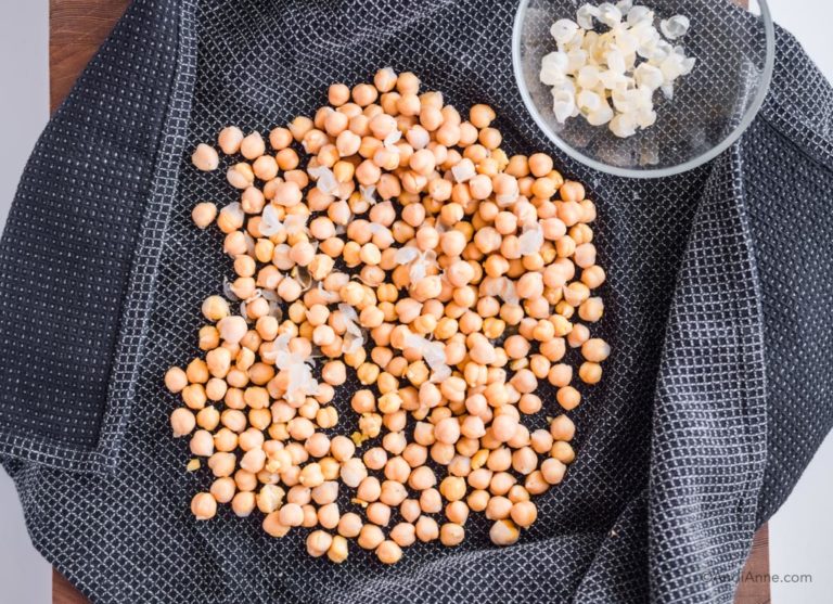 chickpeas on a black towel with shells in a small glass bowl