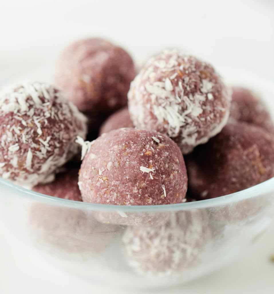 A glass bowl of with the energy balls stacked inside