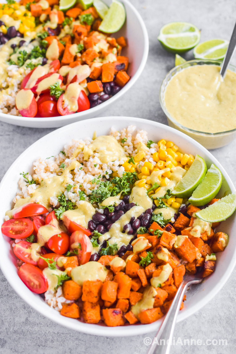 Two sweet potato taco bowls with a small avocado dressing bowl beside them. 