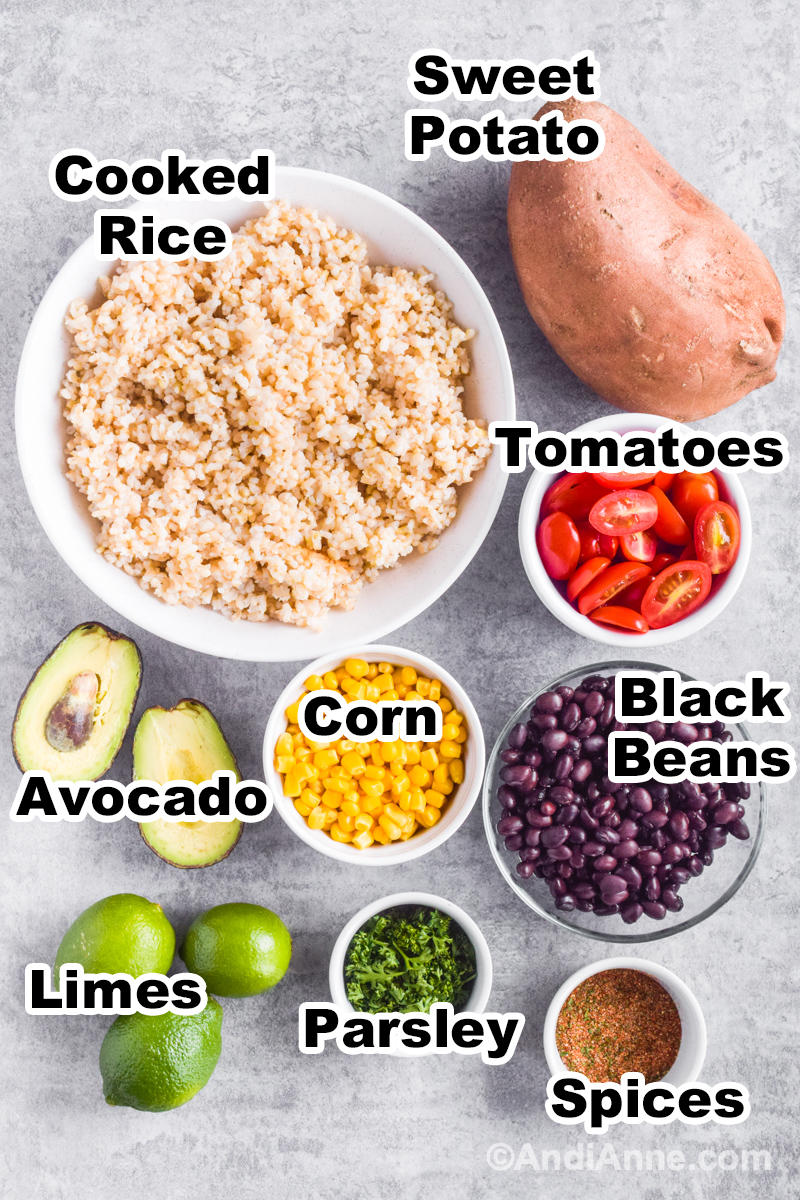 Recipe ingredients including bowl of rice, sweet potato, bowl of sliced grape tomatoes, bowl of black beans, corn, avocados, limes and spices.