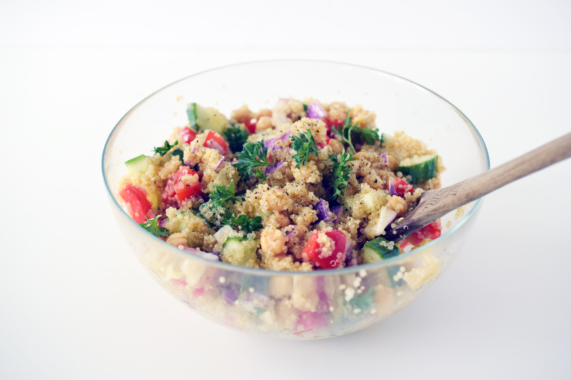 honey dijon quinoa salad in glass bowl with wooden spoon