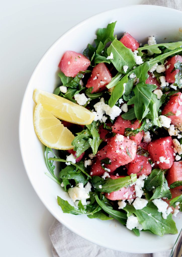 watermelon arugula salad with lemons in a white bowl