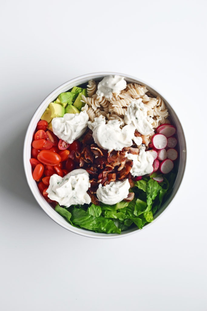 ingredients in a white bowl with dressing dolloped on top