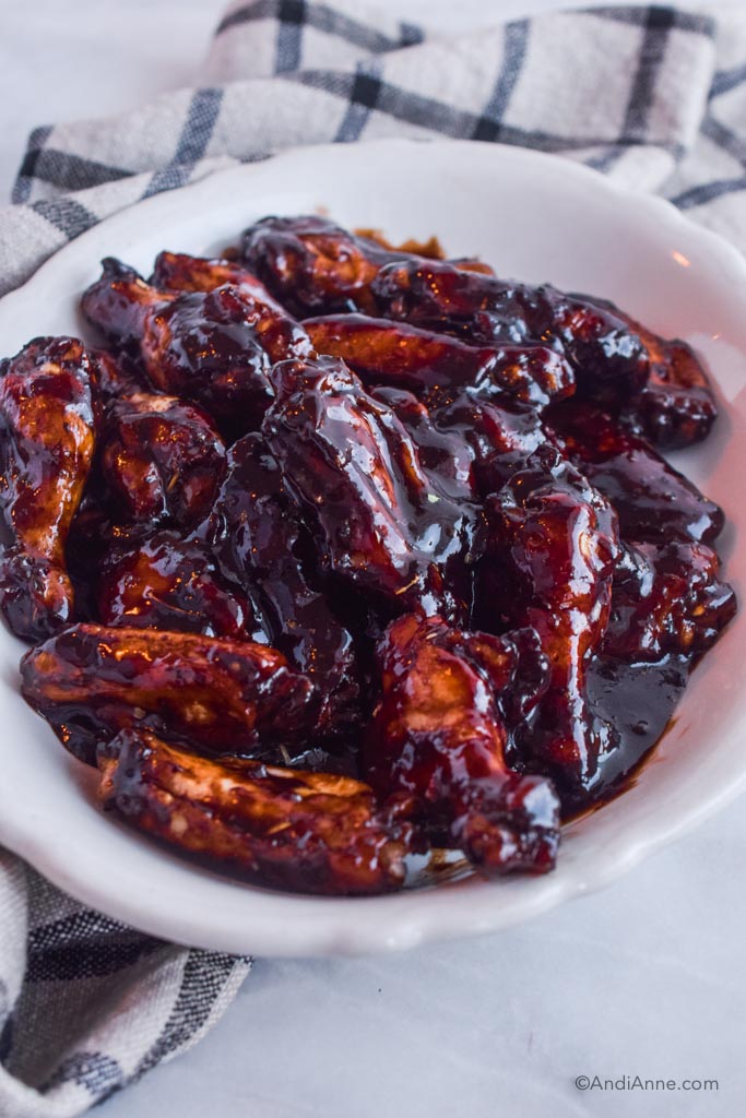 balsamic glazed chicken wings in a white dish with kitchen towel in background.