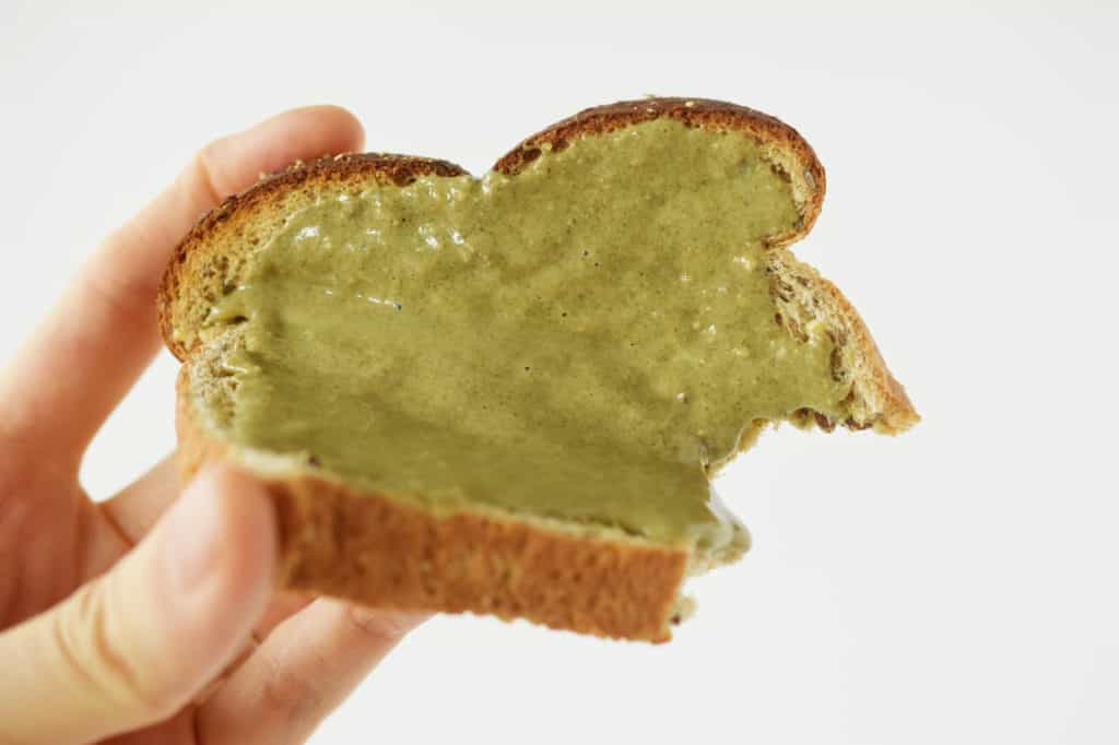 hand holding sunflower seed butter on toast with bite taken out of it