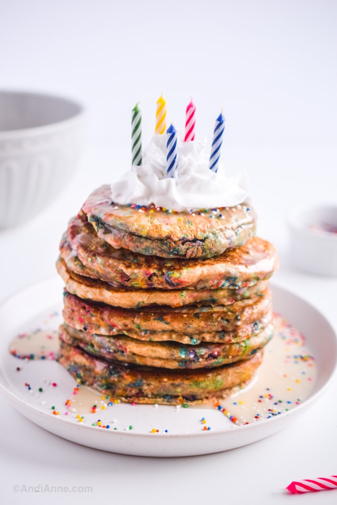 birthday sprinkle pancakes with whipped cream on top and colored candles