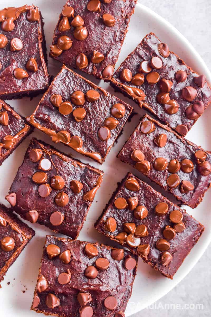 Close up of brownies with chocolate chips on top sitting on a plate.