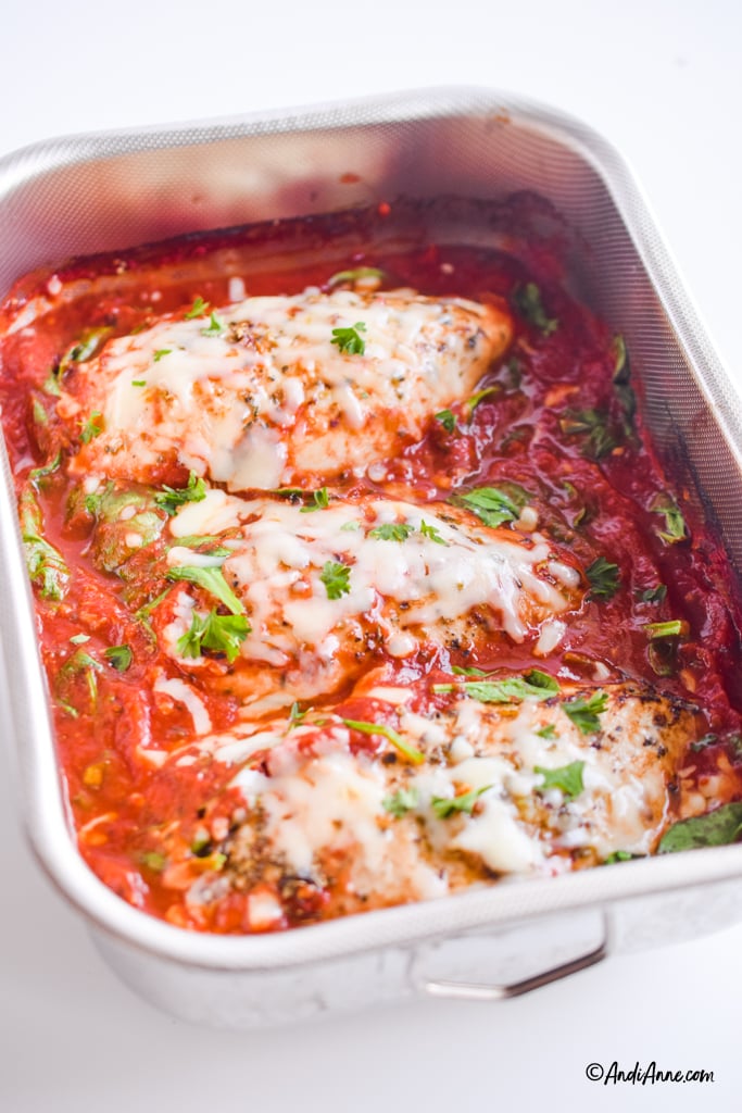 mozzarella chicken in tomato sauce recipe in stainless steel casserole dish. Parsley sprinkled on top of recipe.