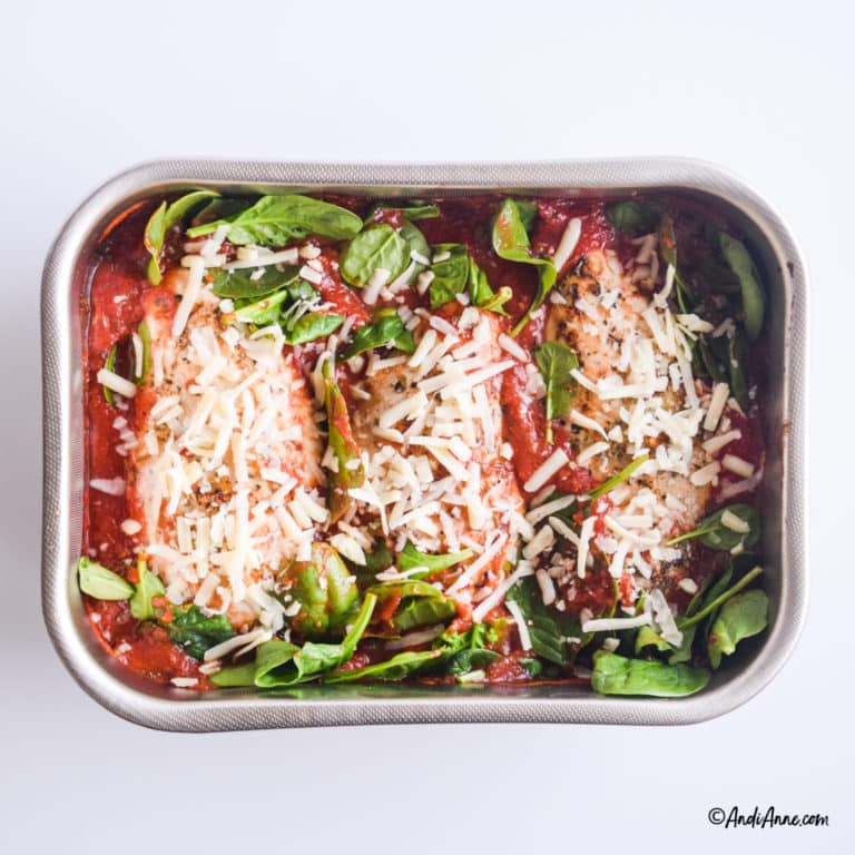 fresh mozzarella cheese and raw spinach are sprinkled on top of the chicken in tomato sauce