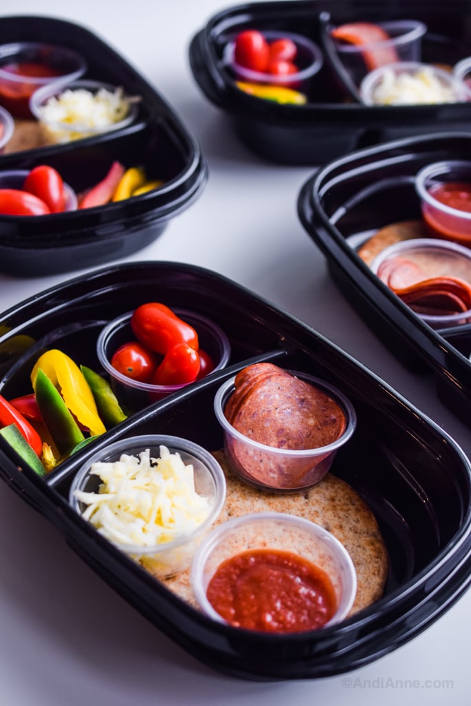 Close up detail of black meal prep containers with smaller clear cups inside holding ingredients separately