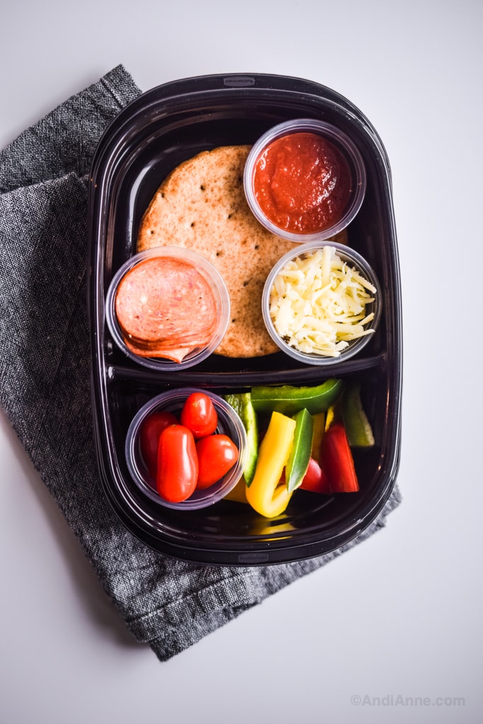 homemade pizza lunchables in meal prep container on a counter with a cloth