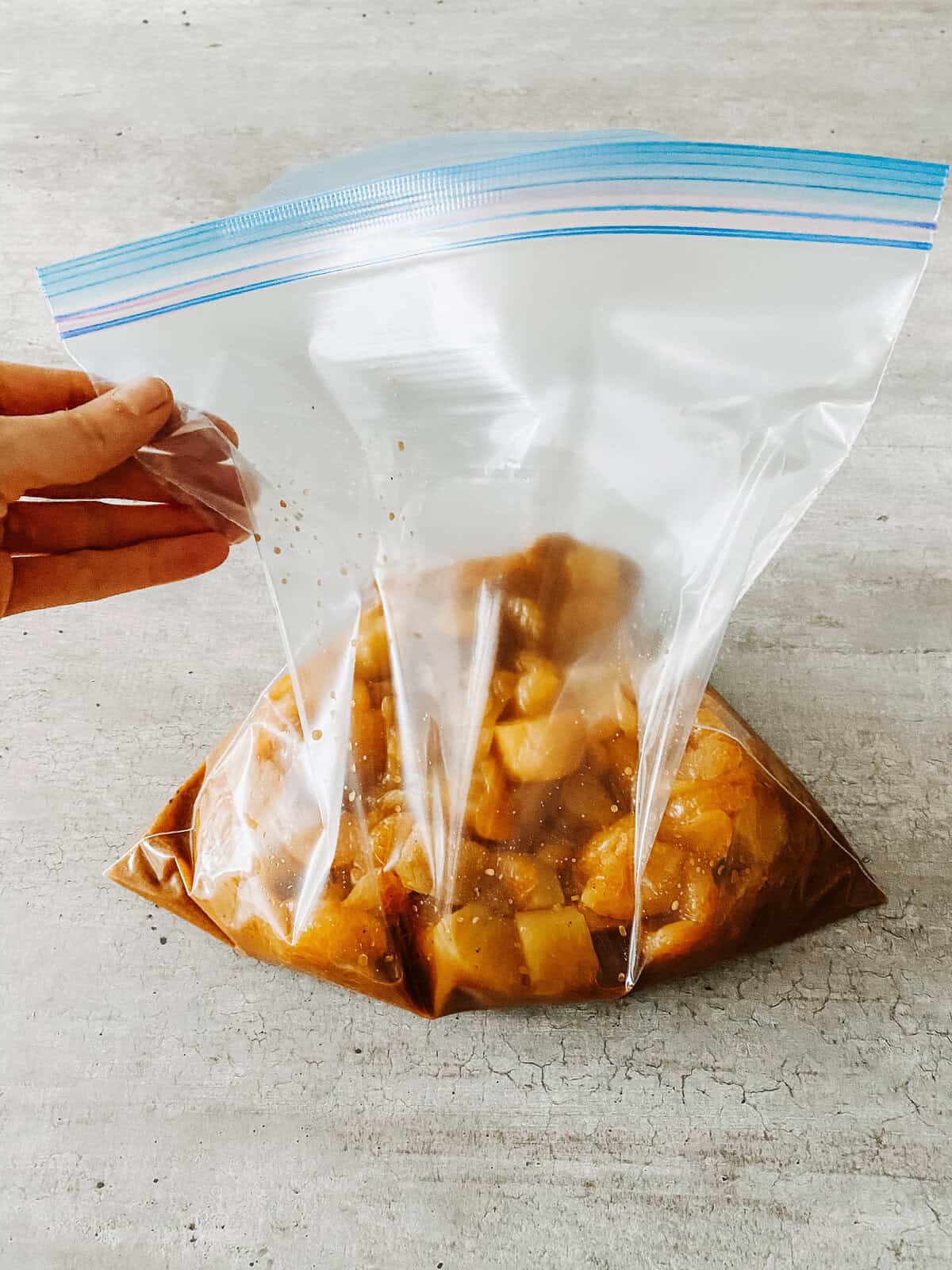 chicken marinade with pineapple and mandarin oranges poured into a freezer bag
