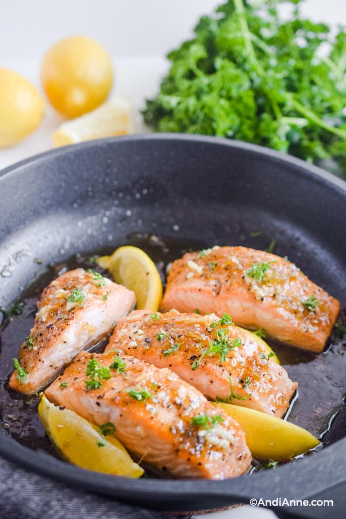 honey garlic salmon fillets in a frying pan with lemons