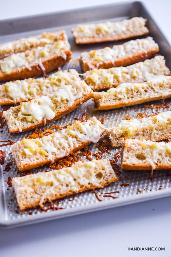 strips of french bread cut up with melted mozzarella cheese on a baking sheet