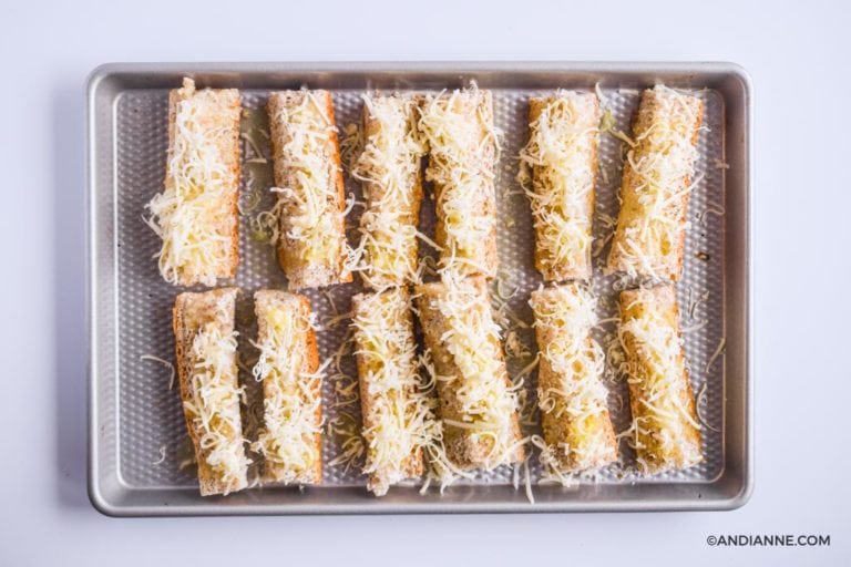 sprinkled mozzarella cheese over top of bread slices on baking sheet