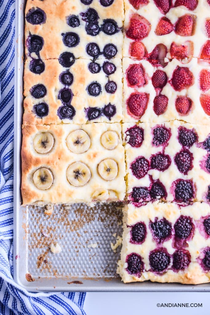 one slice removed from sheet pan pancakes. Close up detail with slices of bananas, blackberries, raspberries and blueberries on top.