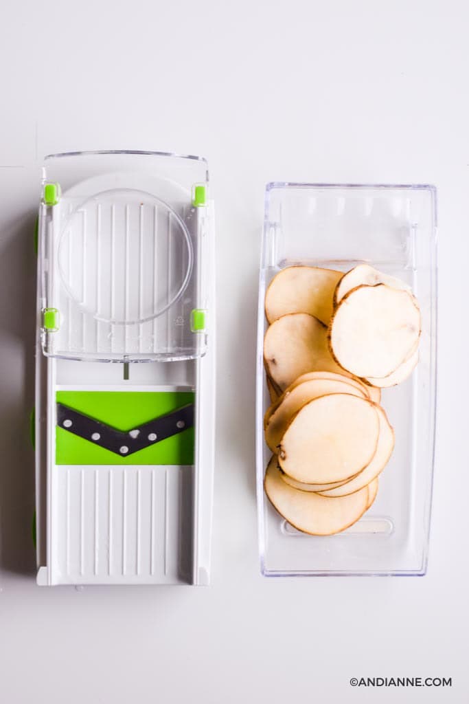 sliced potatoes in a white and green mandolin slicer