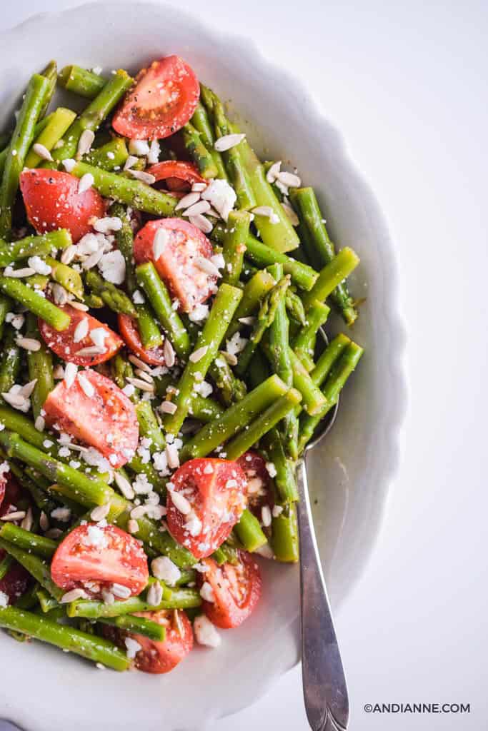 side of asparagus tomato feta salad in white scalloped edge bowl with spoon