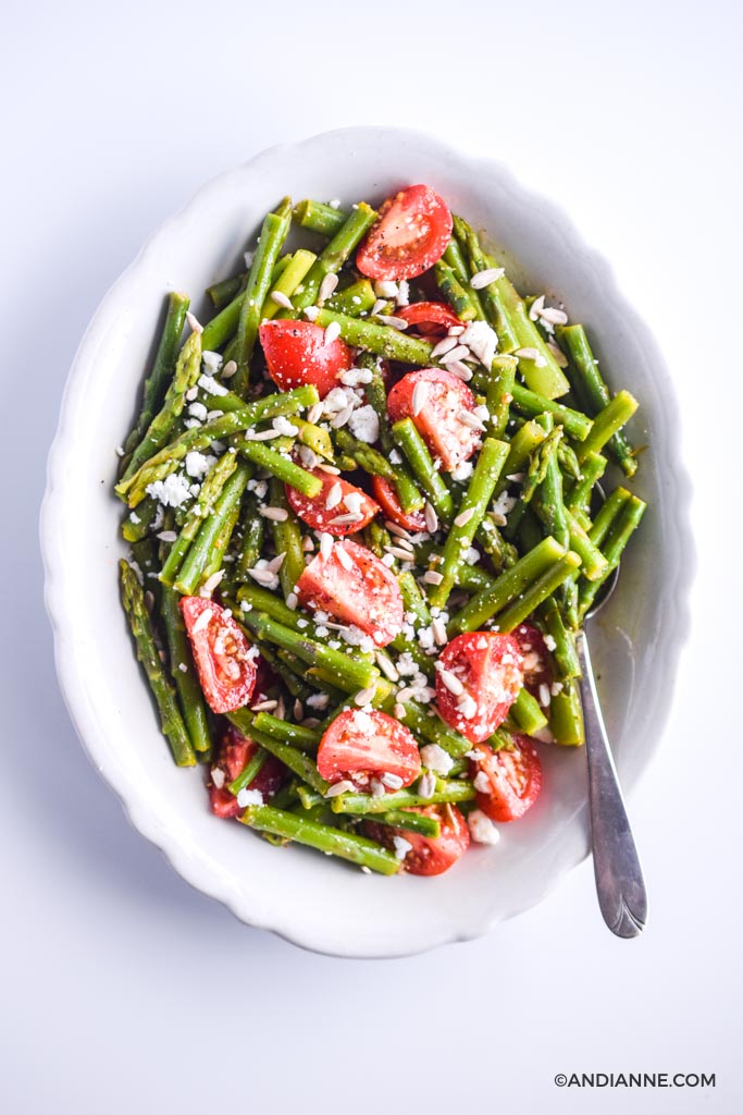 asparagus tomato feta salad in white scalloped edge bowl with spoon