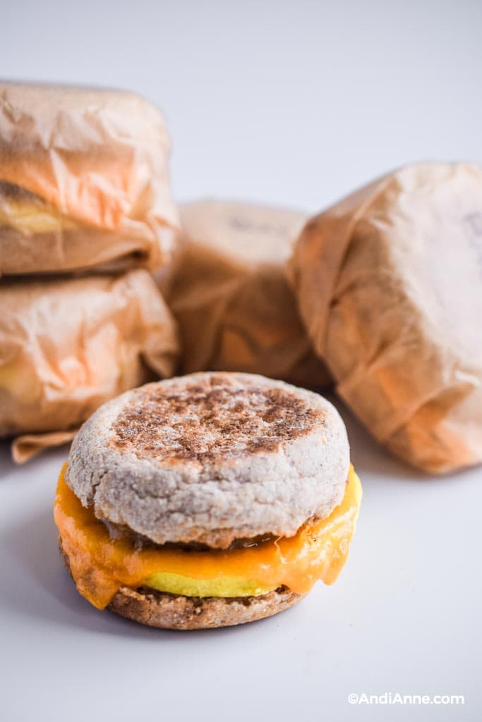 freezer breakfast sandwich with stacked sandwiches behind it wrapped in parchment paper.