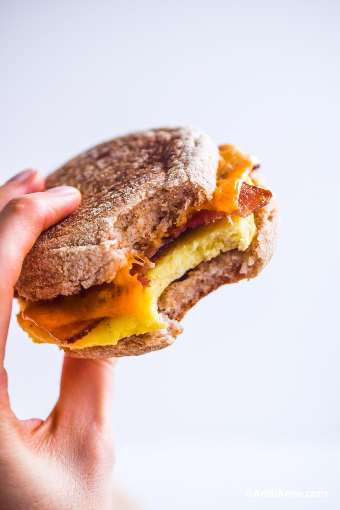 Close up holding a breakfast sandwich with a bite out of it.