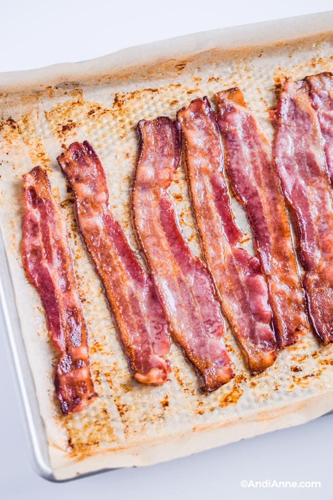 cooked bacon in the oven on parchment paper on a baking sheet