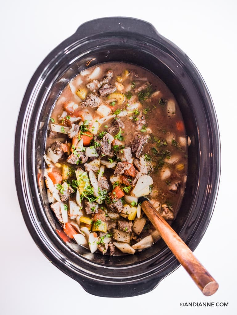 sweet potato beef stew in a crockpot slow cooker with wooden spoon