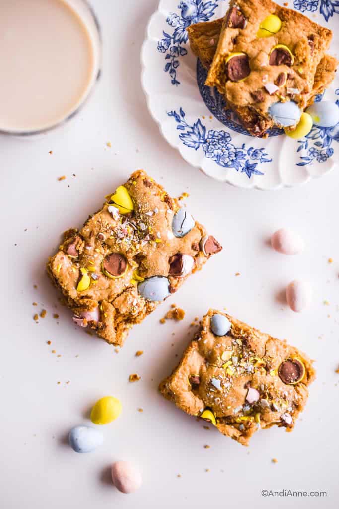 mini egg cookie bars cut out with small white and blue plate and glass of milk on white counter