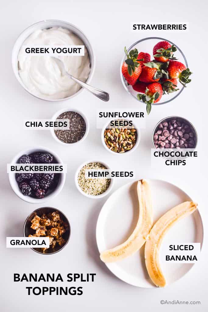Ingredients in separate small bowls on white counter. Banana is sliced in half on a white plate.