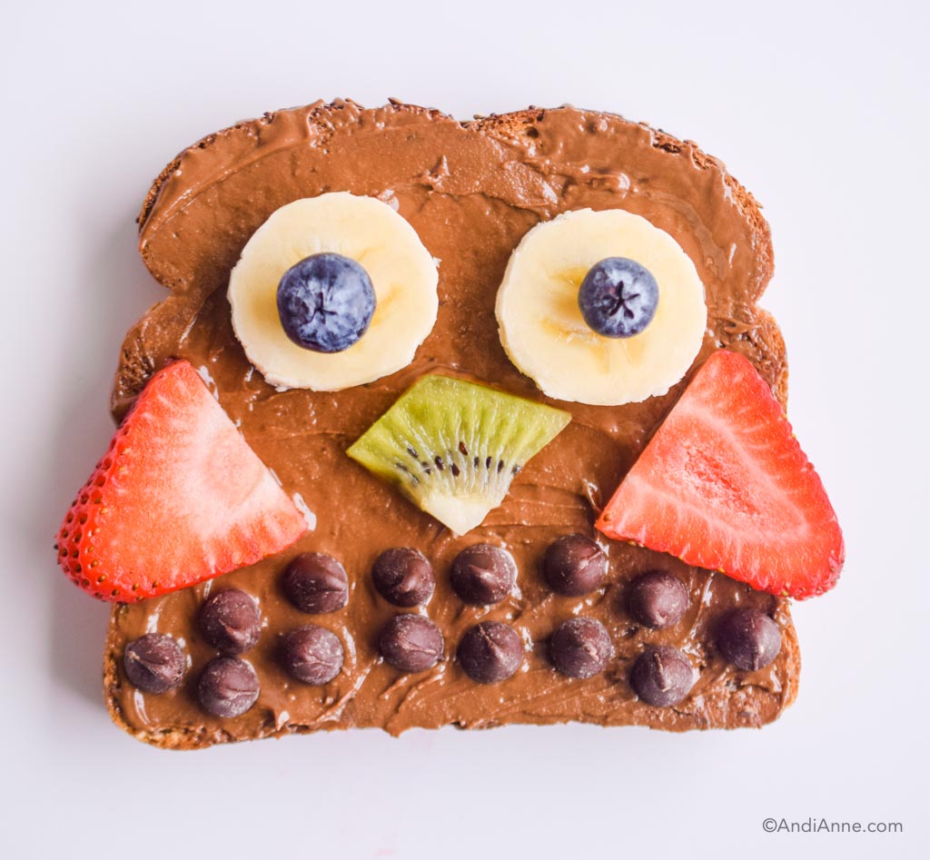 chocolate nut butter on toast with fresh berries and chocolate chips to form an owl shape