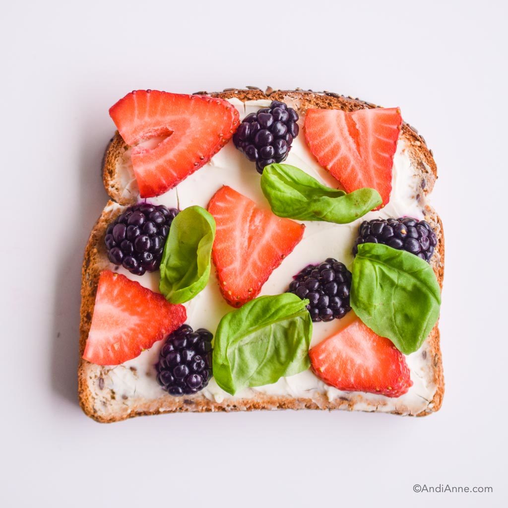 cream cheese toast with fresh sliced strawberries, sliced blackberries, and fresh basil
