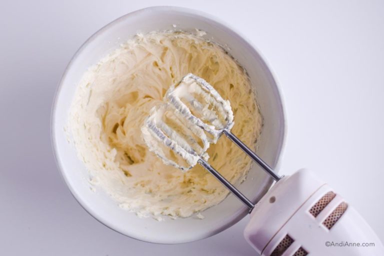 cream cheese icing in white bowl with electric mixer