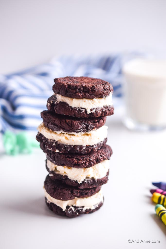 four stacked homemade oreos on top of eachother. Blue striped napkin and milk in the background, crayons in foreground