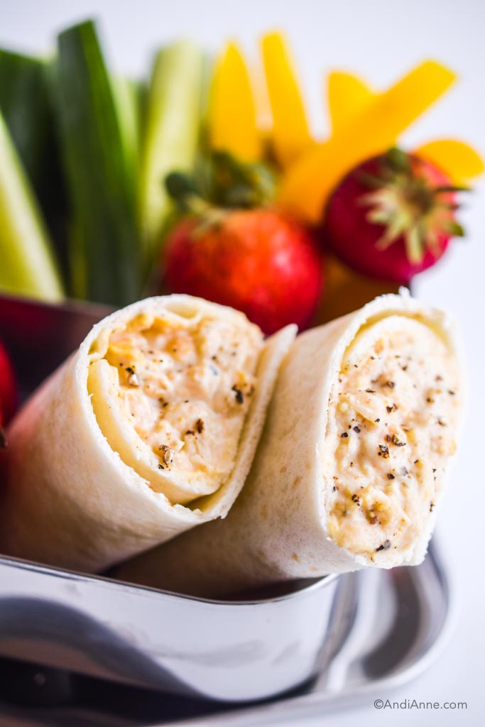 mashed chickpea wraps with strawberries, yellow bell pepper and cucumber in background.