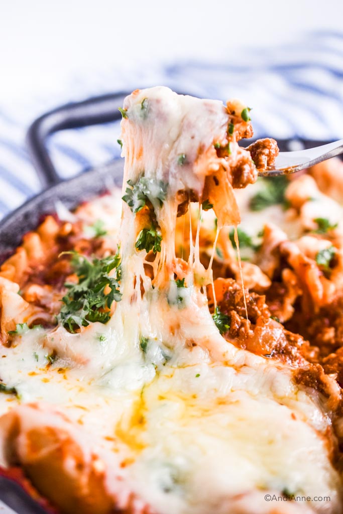 fork pulling up melted cheese from skillet lasagna