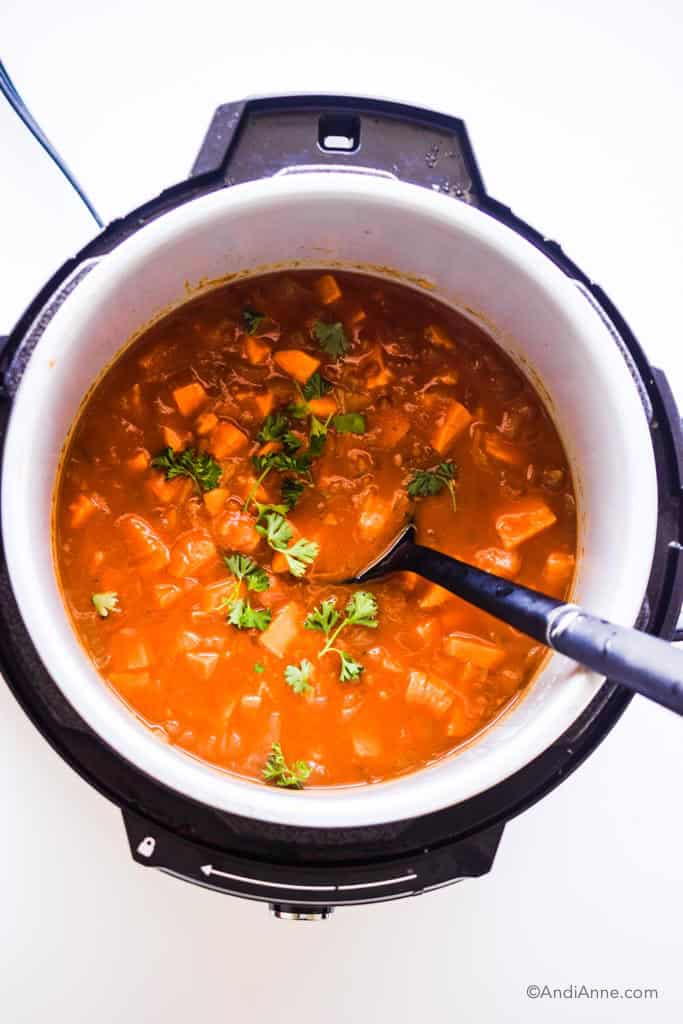 sweet potato soup in an instant pot with a black soup spoon