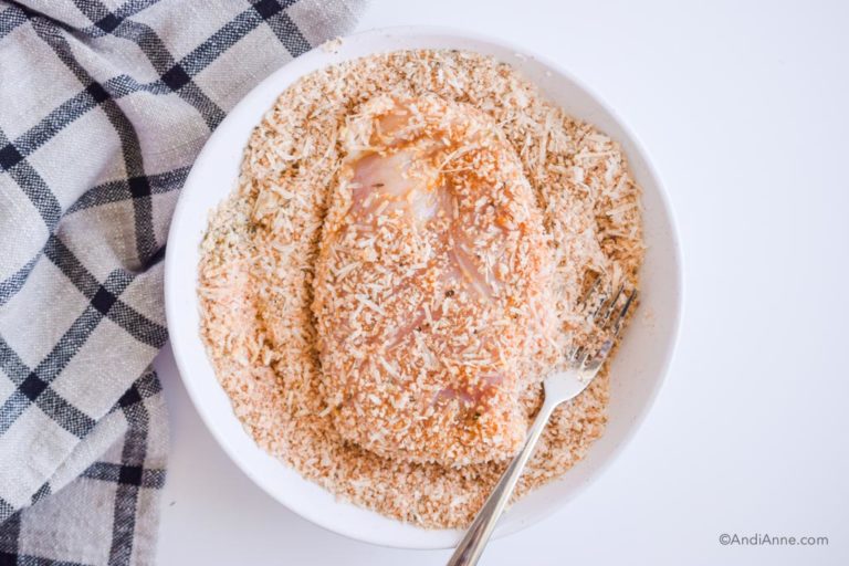 raw chicken on a white plate with parmesan coating around it