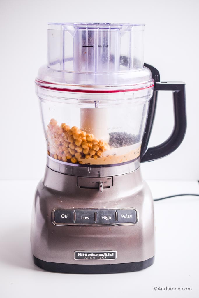 chickpeas, chocolate chips, tahini and other ingredients in a KitchenAid food processor with grey base and black handle.