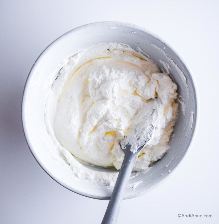 whipped cream in a white bowl with spatula