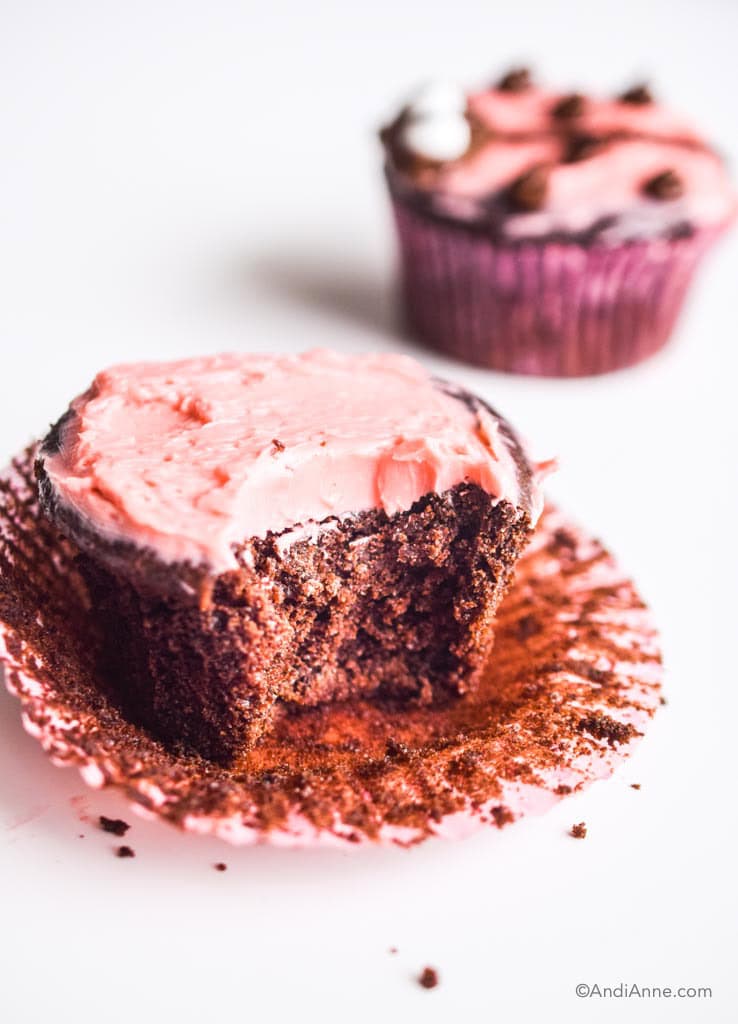 bite taken out of chocolate cupcake with pink icing
