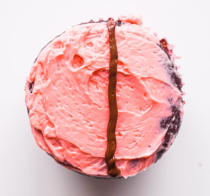 chocolate cupcake with pink icing and chocolate line drawn down the cetner