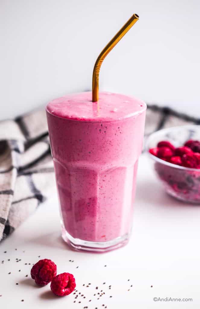 raspberry yogurt smoothie with bowl of raspberries and a few sprinkled chia seeds in front of it