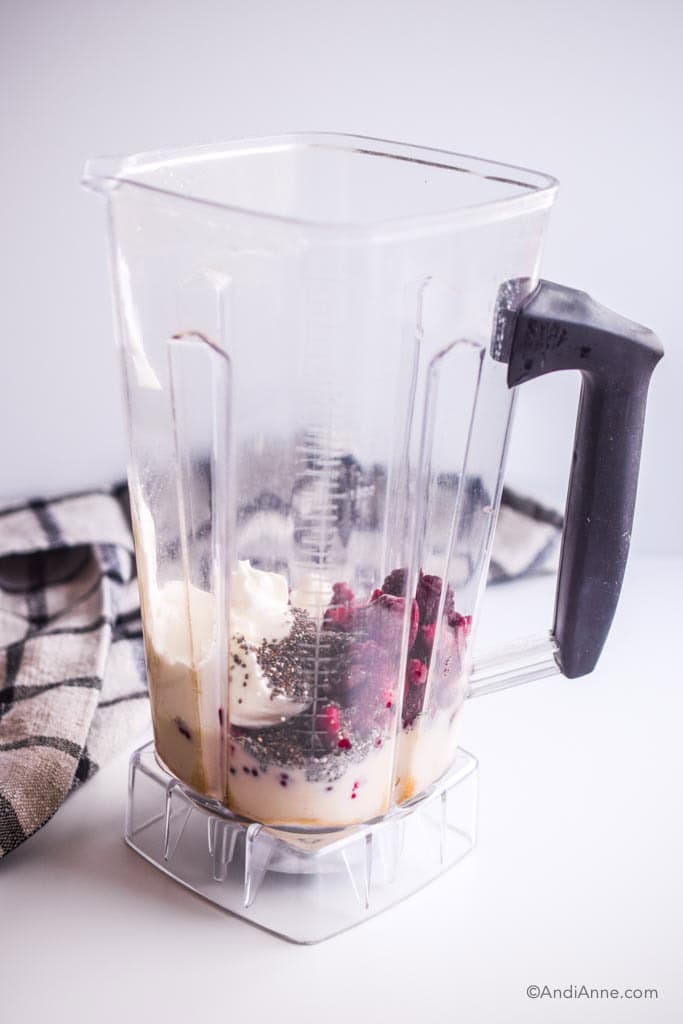 Blender with all the ingredients in it and a kitchen napkin behind it.