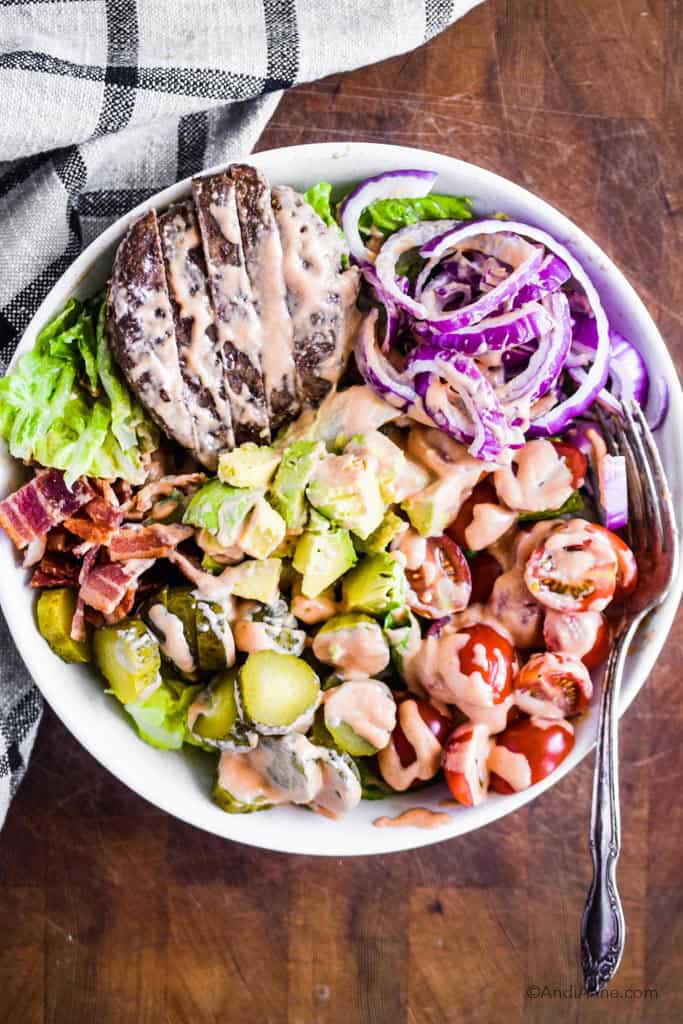 burger salad bowl with special sauce dressing drizzled overtop.