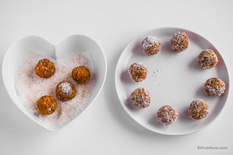 white heart shaped plate with shredded coconut and four energy balls beside a white circle plate and finished rolled carrot cake bites