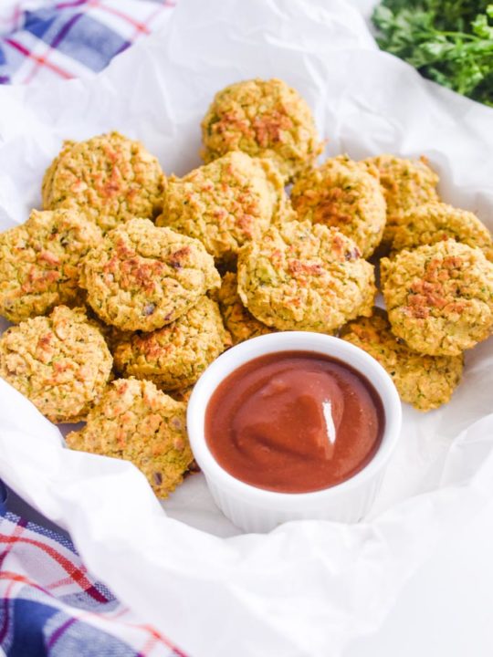 chickpea nuggets piled into crumpled white parchment paper along with a cup of ketchup. 