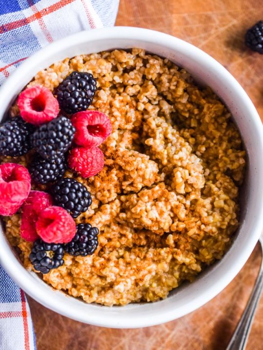 instant pot steel cut oats in a white bowl with fresh berries and cinnamon.
