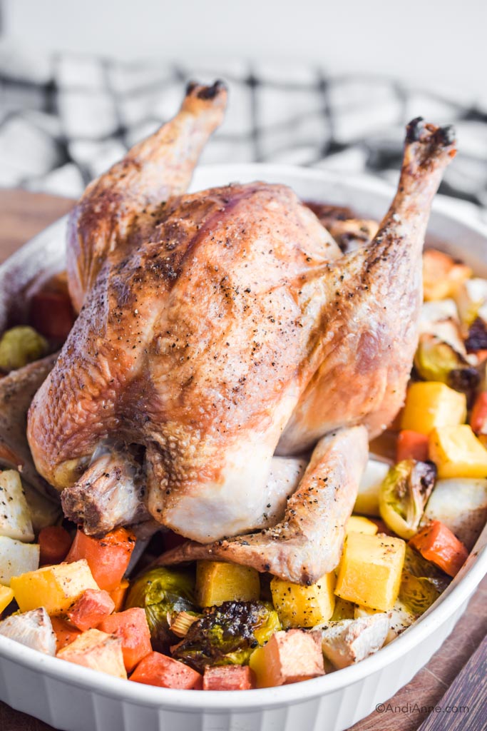 roasted chicken with root vegetables on a cutting board with kitchen towel in the background